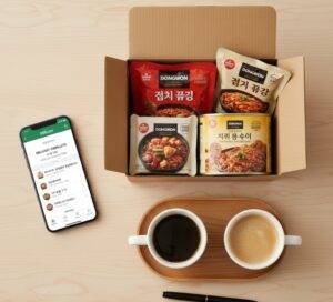 스마트폰으로 본 SSG닷컴 새벽배송 'DELIVERY COMPLETE' 화면과 함께, 배송된 상품이 담긴 종이박스, 커피 두 잔, 펜이 놓여있는 상단 뷰.