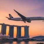 싱가포르 마리나 베이 샌즈 상공을 석양 속에서 비행하는 싱가포르 항공 비행기