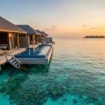 두짓 타니 몰디브의 워터빌라들이 석양을 배경으로 에메랄드빛 바다 위에 늘어서 있으며, 개인 인피니티 풀 아래로 선명한 산호초와 열대어가 보인다.