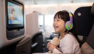 싱가포르 항공 기내에서 헤드폰을 끼고 만화를 보며 즐거워하는 여자 아이