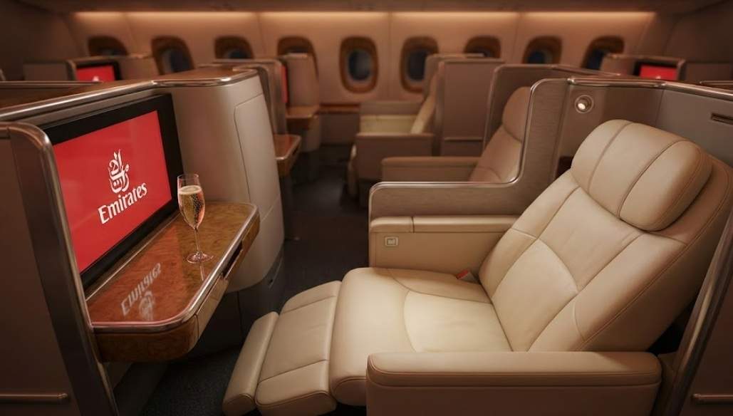 에미레이츠 비즈니스 업그레이드를 통한 A380 비즈니스석의 고급스러운 가죽 좌석과 샴페인 한 잔이 놓여 있는 기내 전경. 2025년 업그레이드 가이드 썸네일.