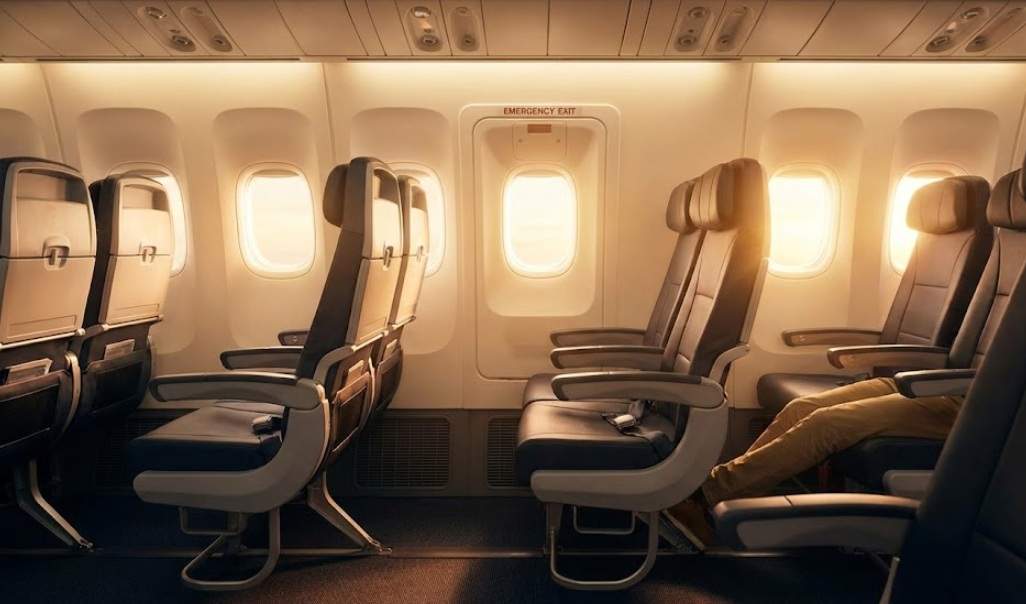 비엣젯항공 비상구 좌석의 넓은 레그룸에서 편안하게 다리를 뻗고 있는 승객의 모습. 창밖으로 따뜻한 햇살이 들어와 아늑한 분위기를 연출한다.