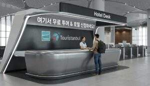 이스탄불 공항 도착 로비에 위치한 현대적인 터키쉬 항공 'Hotel Desk' 및 'Touristanbul' 서비스 카운터. 배낭을 멘 여행자가 직원에게 투어 또는 호텔 신청을 하고 있음.