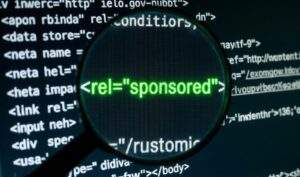 컴퓨터 모니터의 HTML 코드 중 rel="sponsored" 태그를 돋보기로 확대하여 보여주는 테크니컬 SEO 이미지.