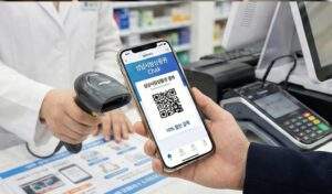 스마트폰 화면에 성남사랑상품권(Chak) 앱의 '10% 할인 결제' QR 코드가 떠 있고, 약국 직원이 바코드 스캐너로 결제하는 클로즈업 사진.